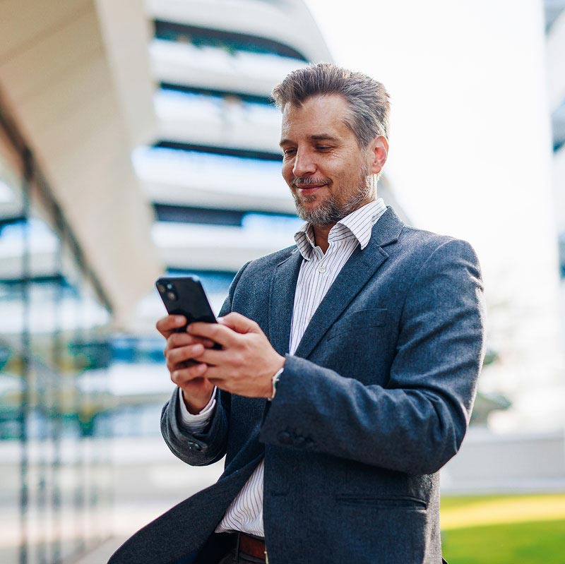 ai-data-section-2 A professional businessman in a suit reviewing data on his smartphone outside an office building, representing an industry specialist for AI training.